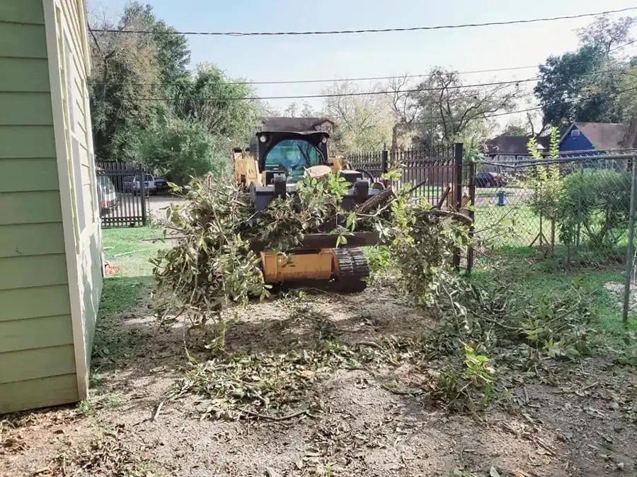 Skid steer clearing brush piles in a backyard