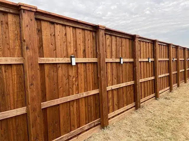 Stained wood fence with cap rail and solar post lights