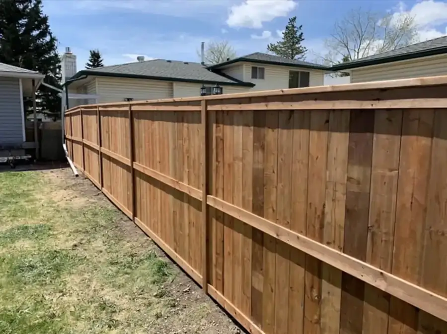 Capped wood privacy fence along a backyard