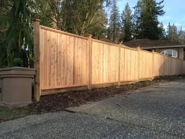 Cedar fence with capped posts along a driveway